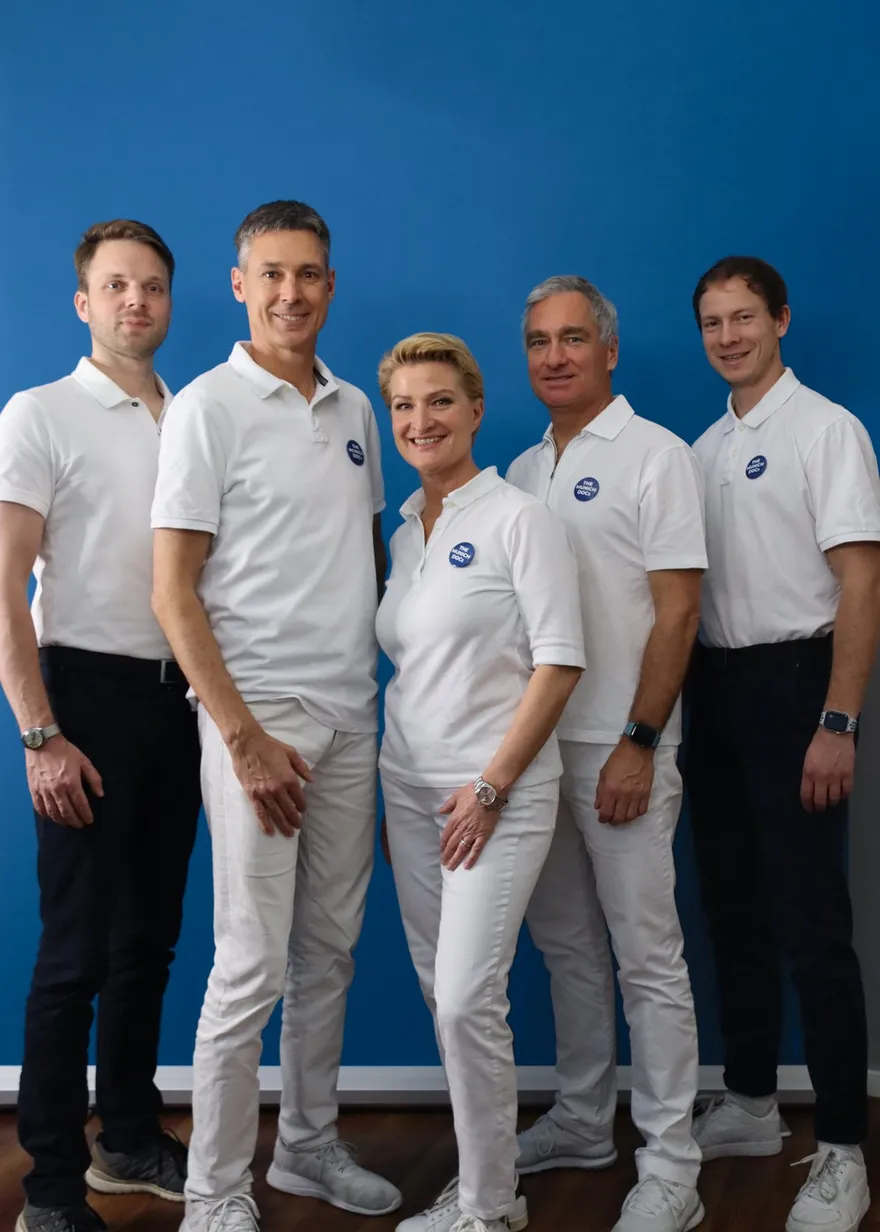 Fünf Mitglieder des Teams von THE MUNICH DOCs vor blauer Wand